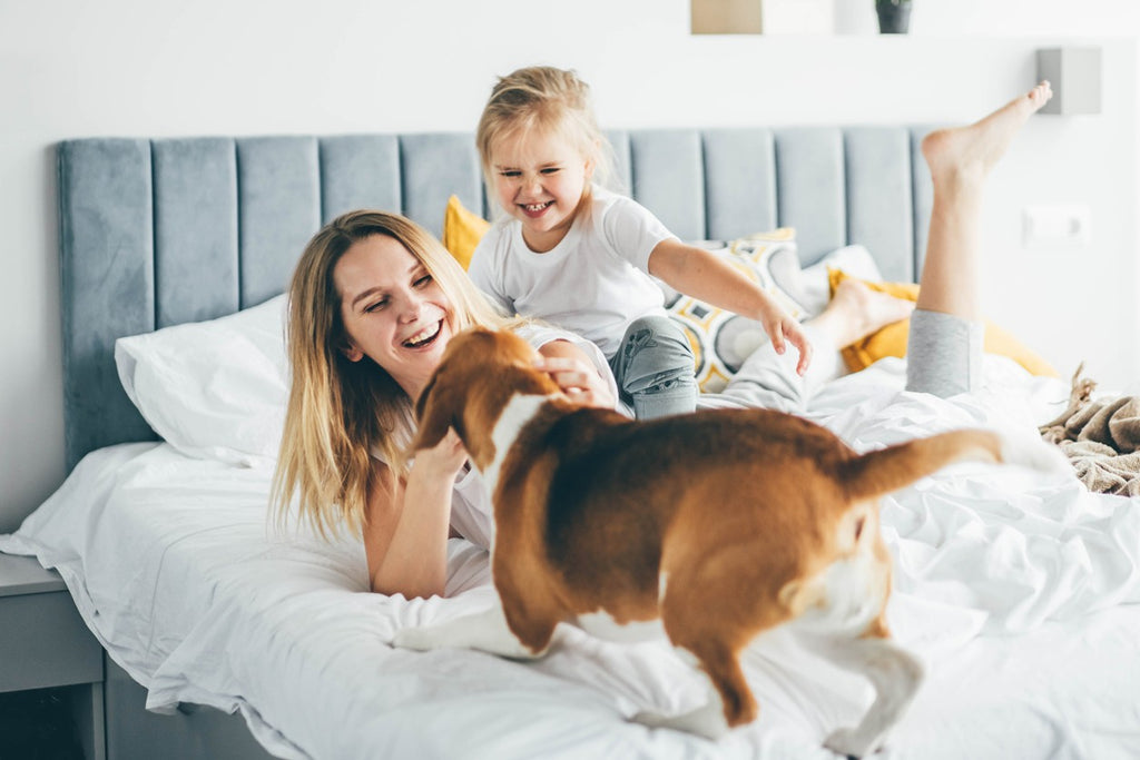mother-and-daughter-playing-with-dog-in-bed